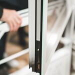 Hand adjusting insulated glass window panel in white frame